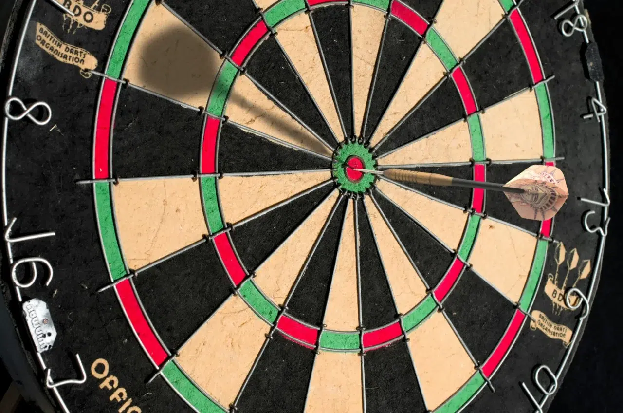 Dart successfully hitting target on black and white board.